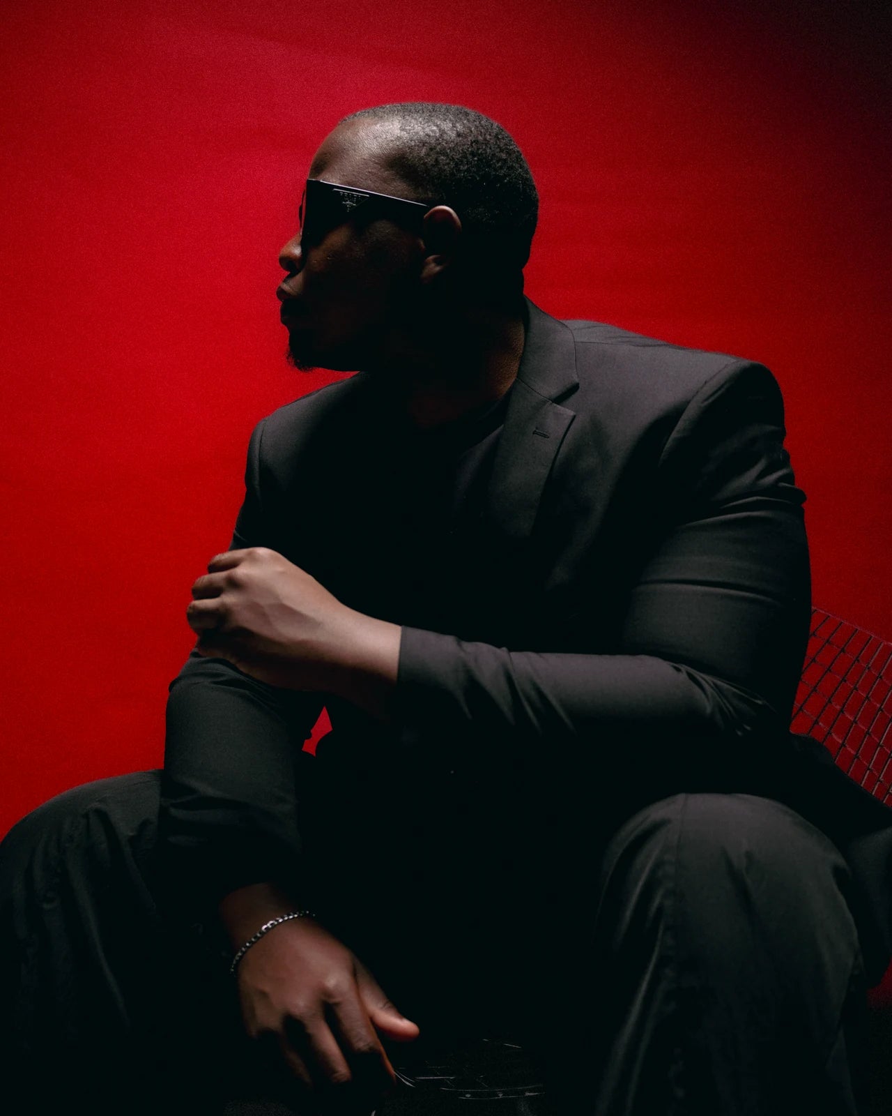 Shawn Pettieway, the creative visionary behind ONE, seated in a tailored suit and sunglasses