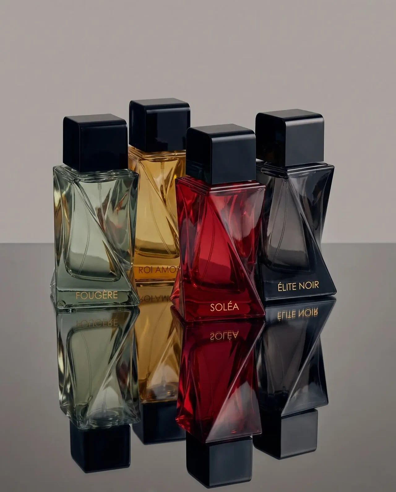 Fougère, Roi Amos, SOLÉA and Élite Noir in faceted bottles reflected on a mirrored surface